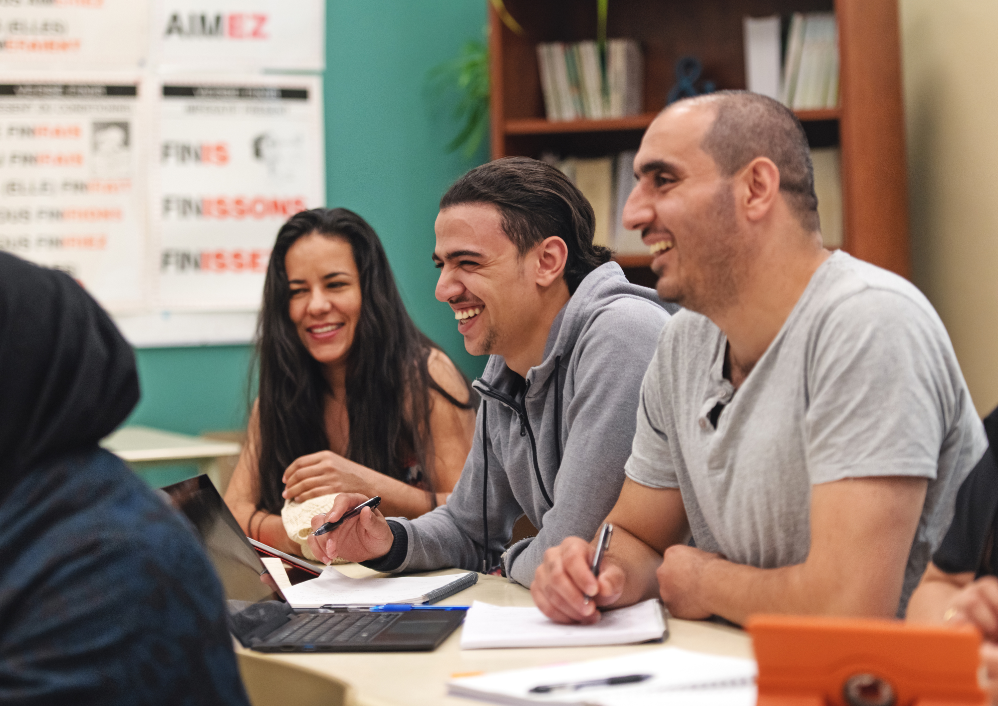Adult learners smiling and taking notes together around a classroom table